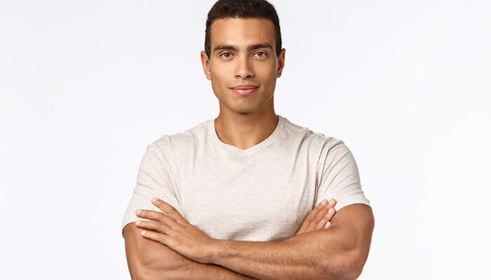 Self-assured and motivated good-looking male athlete in casual t-shirt, cross arms over chest in confident, assertive pose, smirk satisfied and proud, looking strong and powerful, white background.