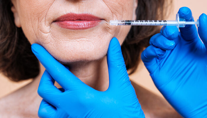 Image of a senior woman getting a beauty treatment. Client of a beauty salon taking a filler injection in the face against wrinkles and aging strokes