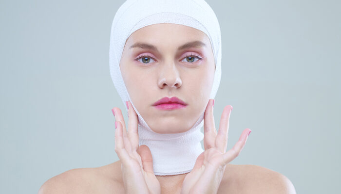 Face with bandage of beautiful young woman after plastic surgery